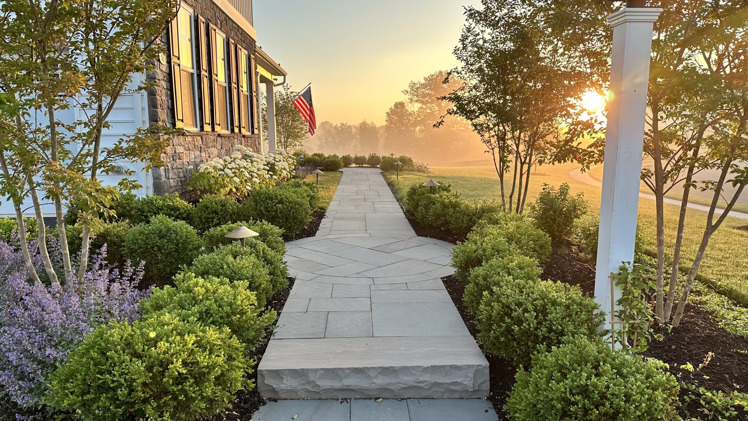Beautiful garden path at sunset with American flag.