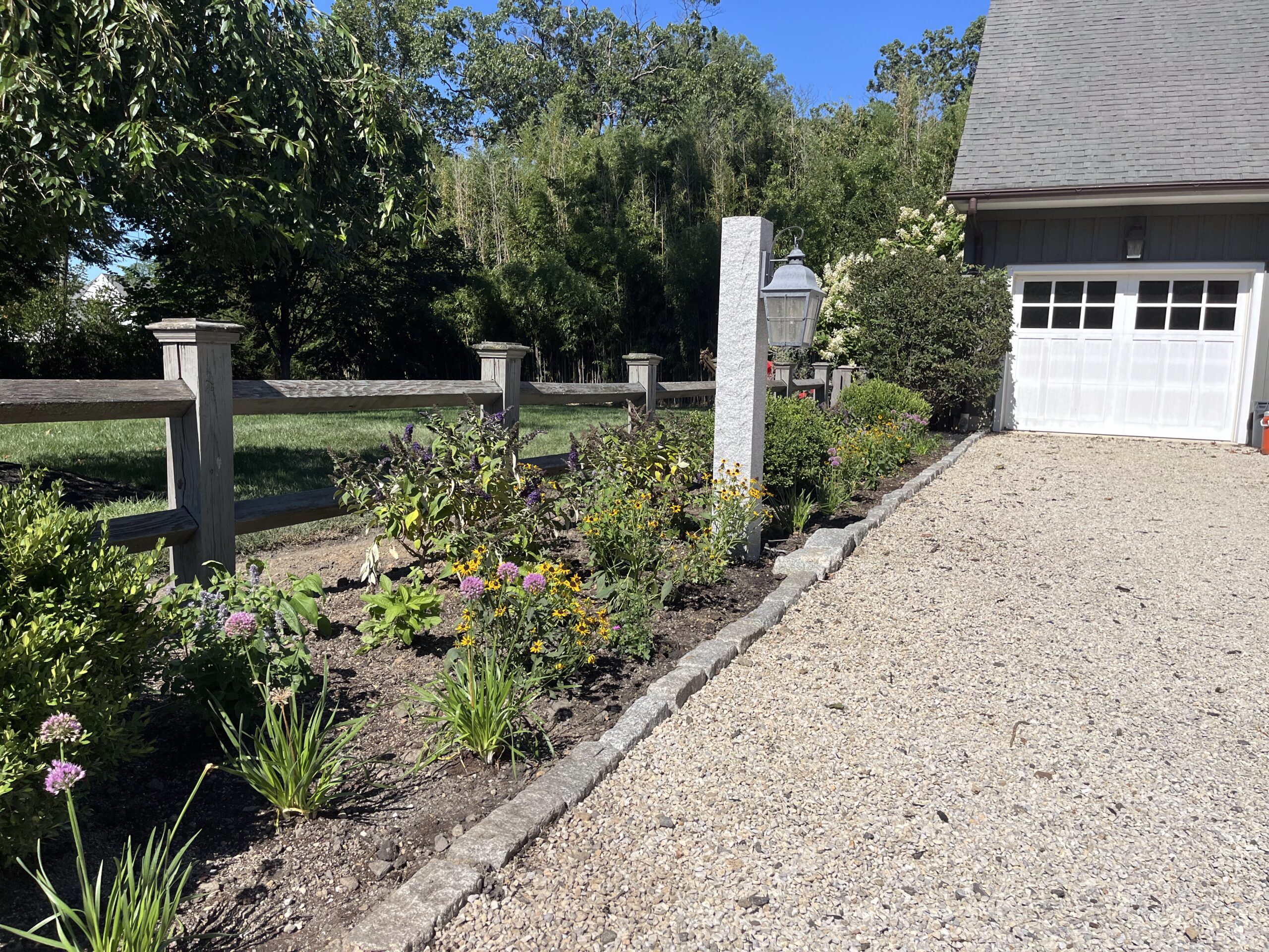 Gravel driveway with flower garden and garage