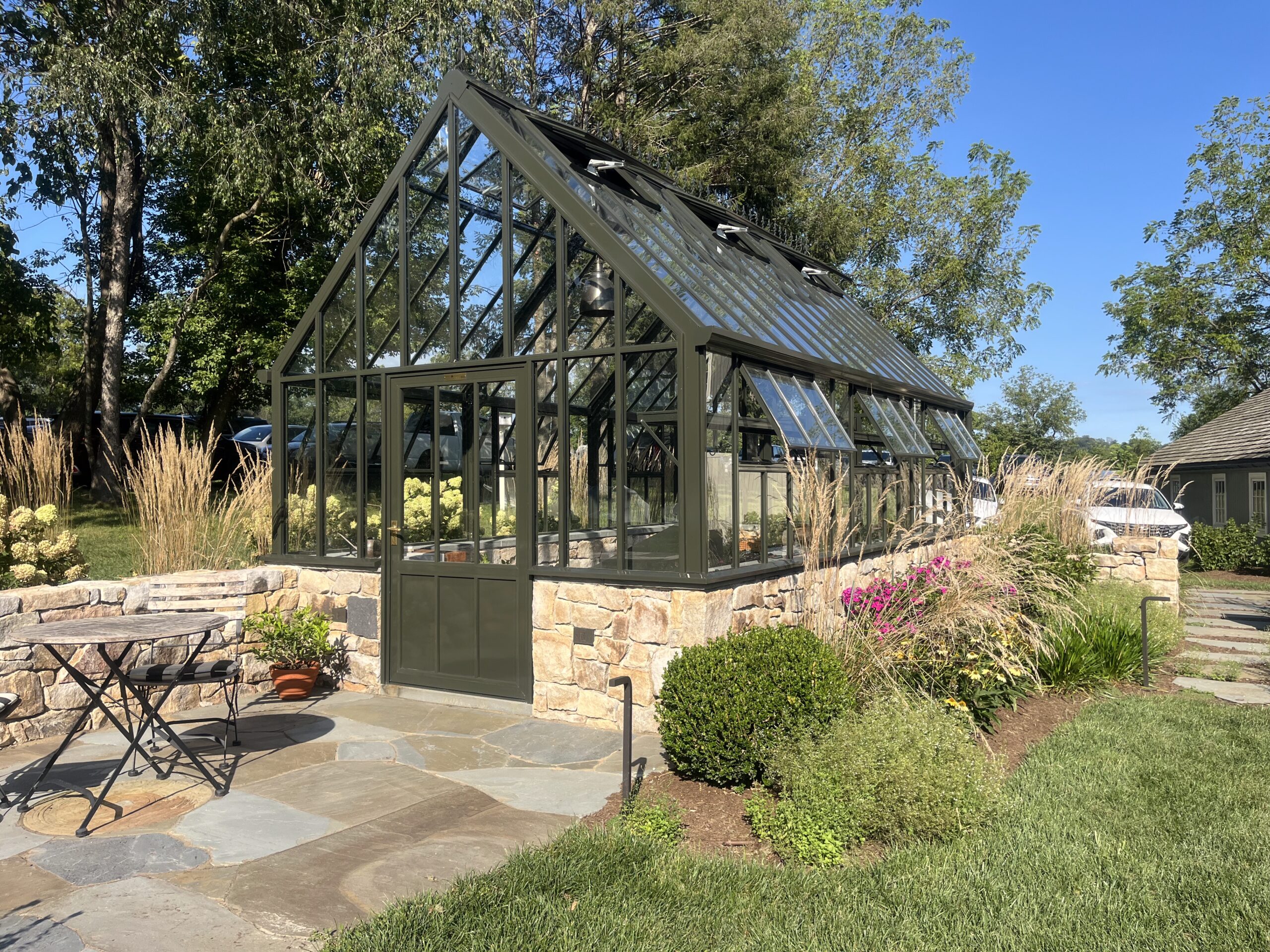 Modern greenhouse with glass roof and garden chairs