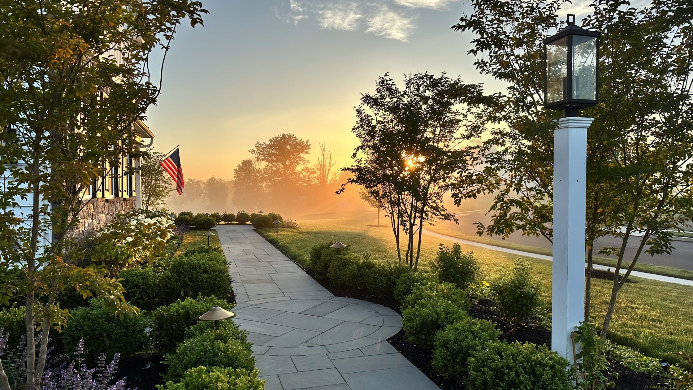 Sunrise over garden path with American flag