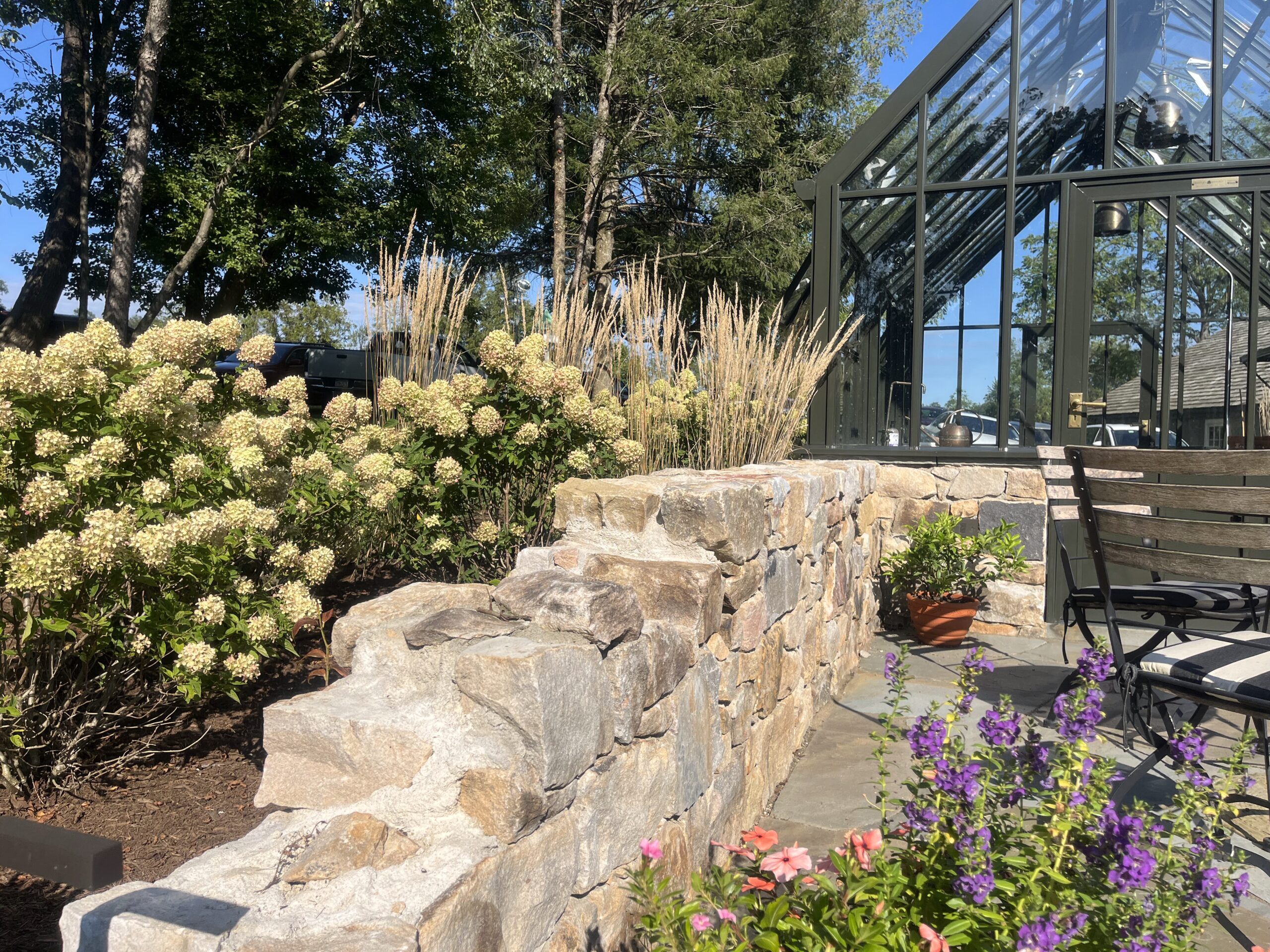Garden with stone wall and glass greenhouse