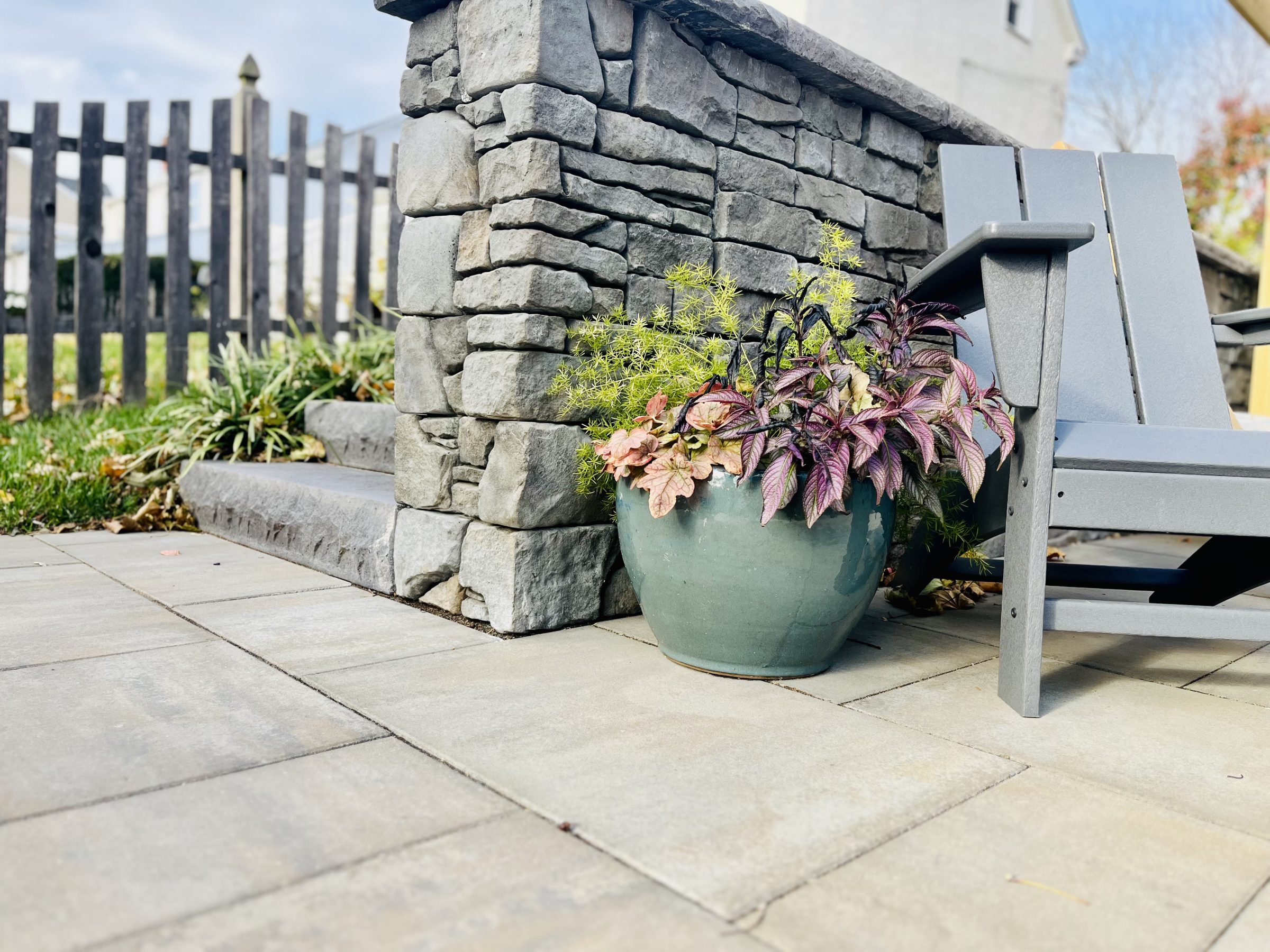 Potted plants beside stone steps and wooden chair.