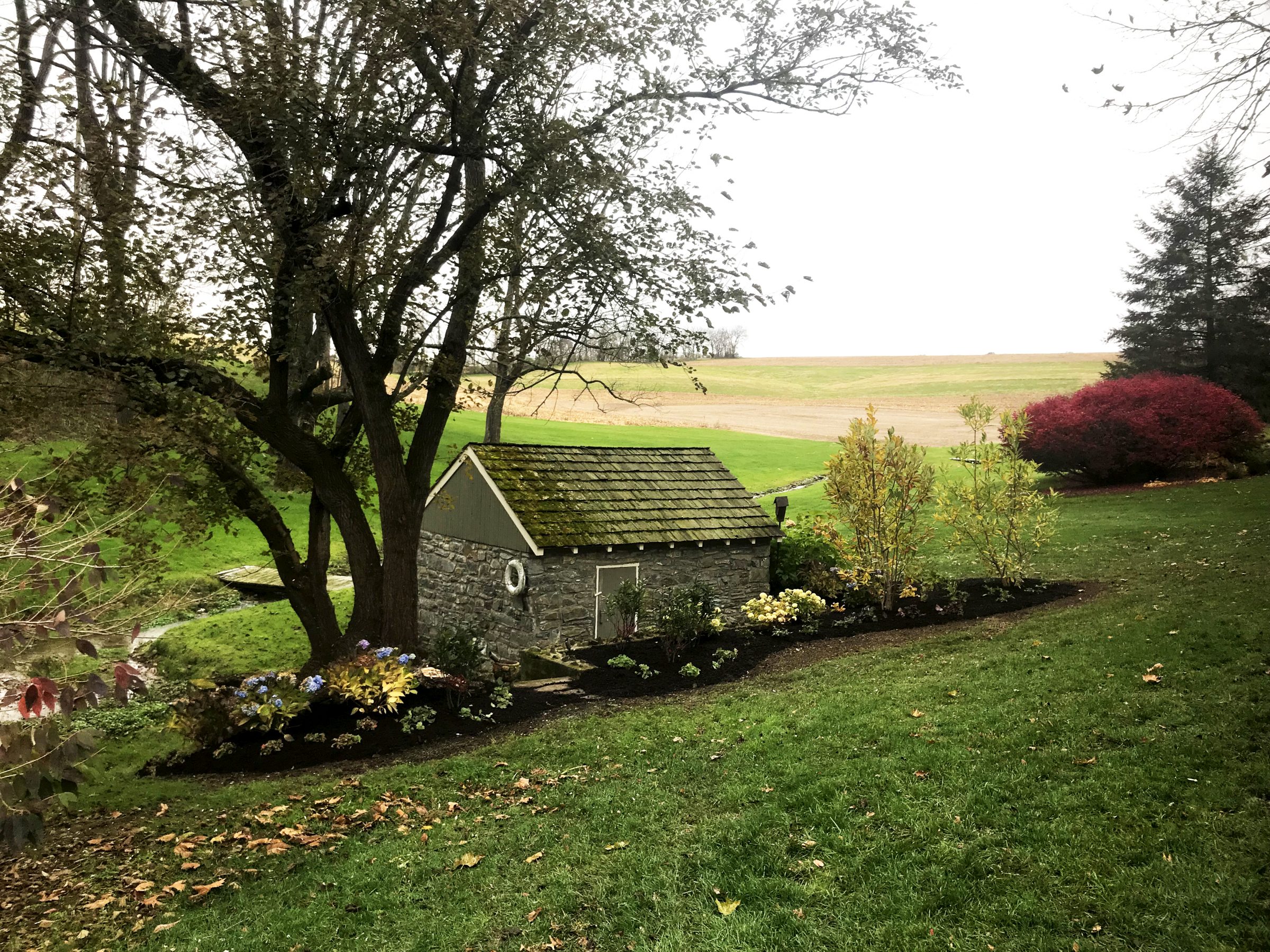 Stone house surrounded by lush green landscape.