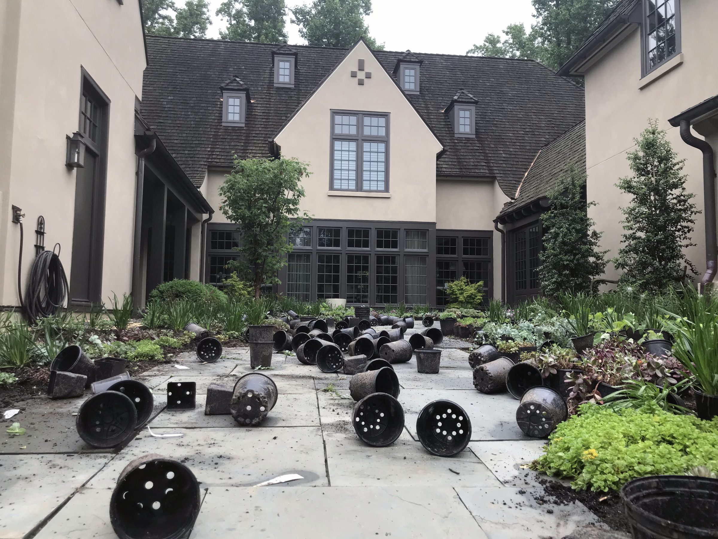 Empty planters scattered on patio near large house.