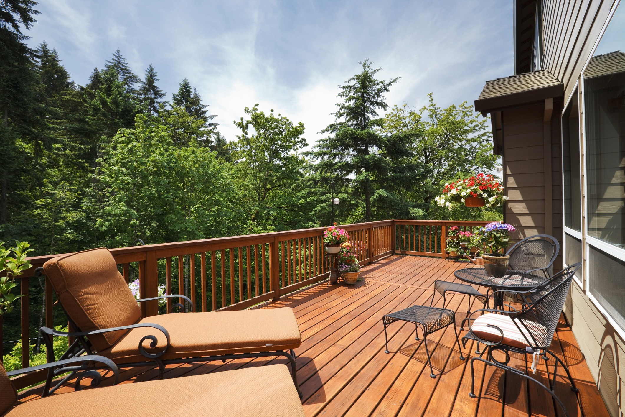 Wooden deck with chairs and garden view.